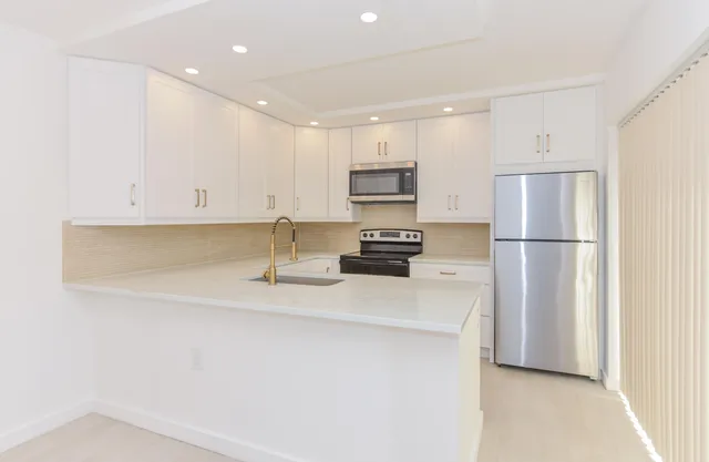a kitchen with kitchen island a sink stainless steel appliances and cabinets