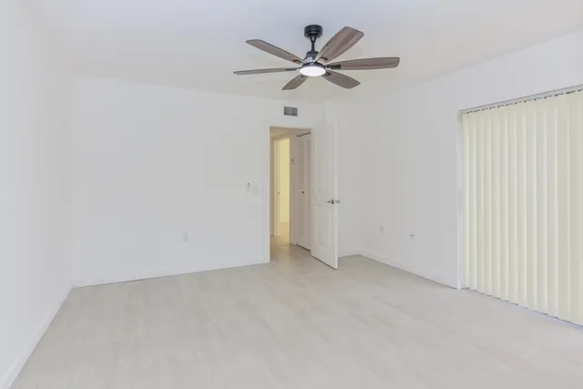a view of a room with a chandelier fan and wooden floor