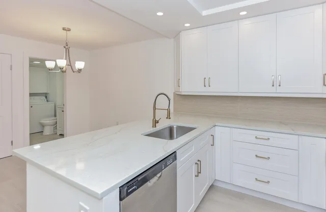 a kitchen with white cabinets and sink