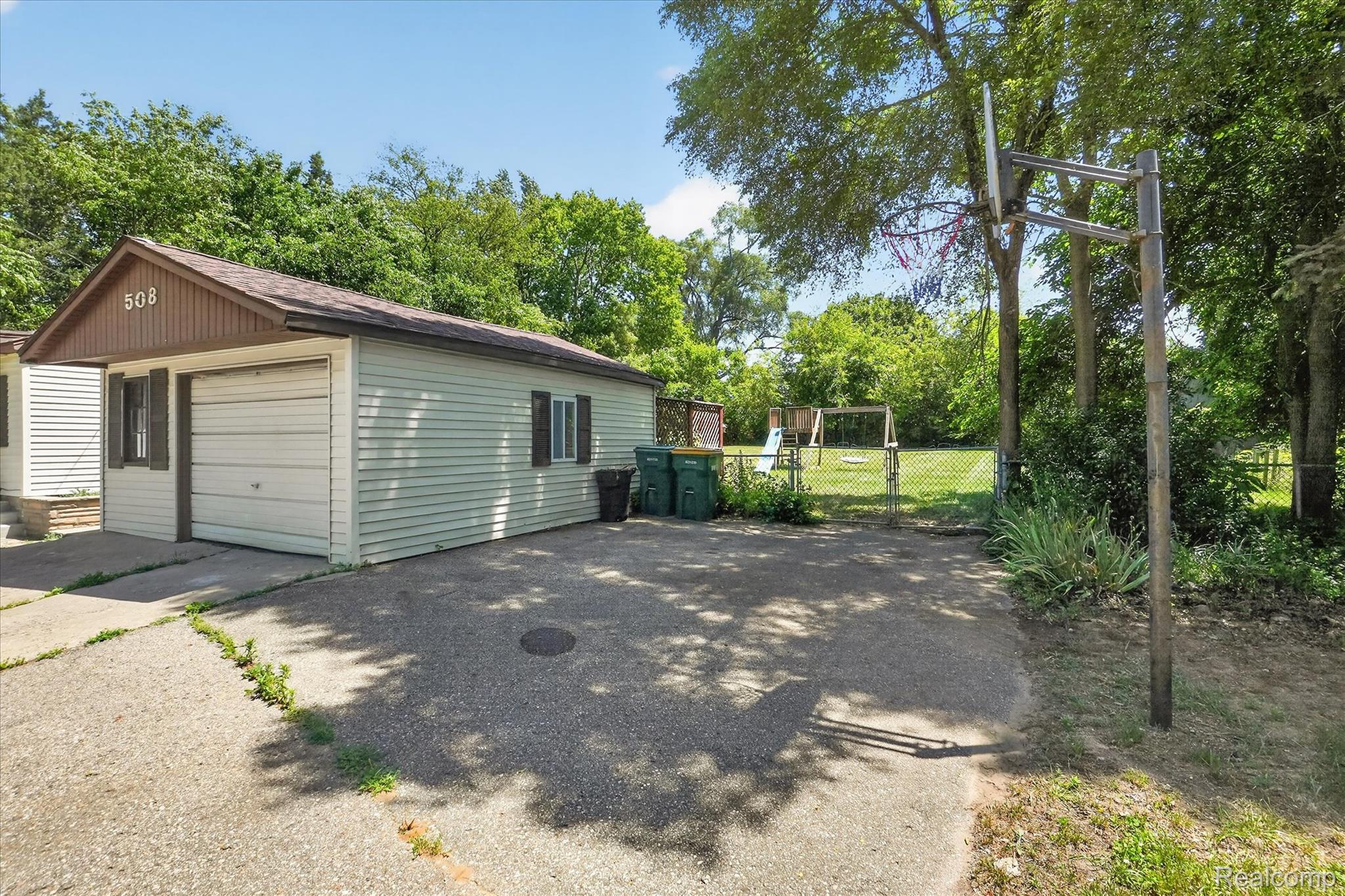 508 Deland Road Flushing, MI 48433 - Photo 37 of 38 Detached garage featuring vinyl siding, a brown shingled roof, and a single garage door