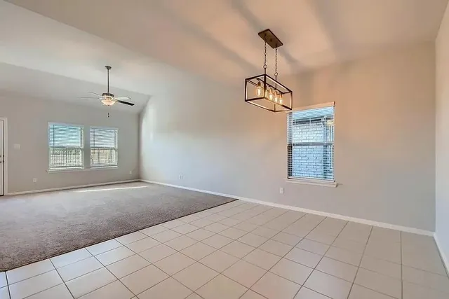 an empty room with windows and ceiling fan