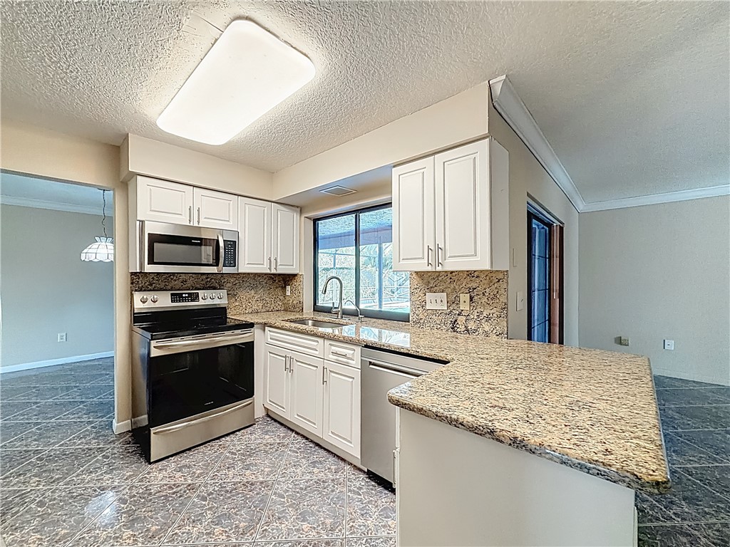 4667 Baldric Street Boca Raton, FL 33428 - Photo 12 of 32 a kitchen with stainless steel appliances granite countertop a stove a sink and a microwave