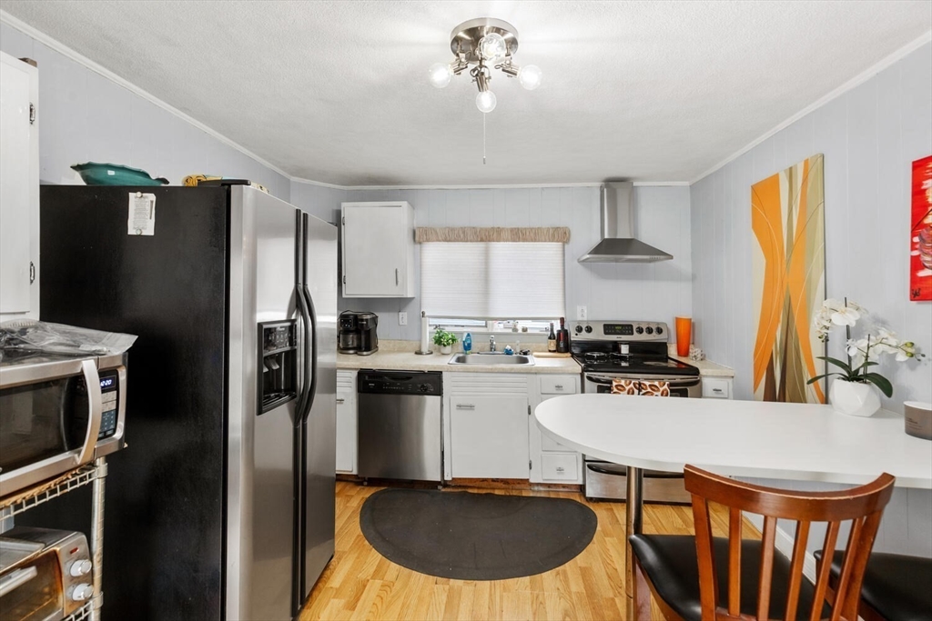 46 Bartlett Street Malden, MA 02148 - Photo 13 of 32 a kitchen with a refrigerator a stove a sink dishwasher a dining table and chairs with wooden floor
