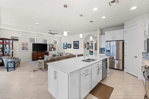 a view of kitchen with stainless steel appliances kitchen island a sink dishwasher a refrigerator and white cabinets with wooden floor