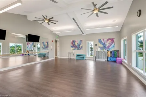 a view of a livingroom with wooden floor a ceiling fan and windows