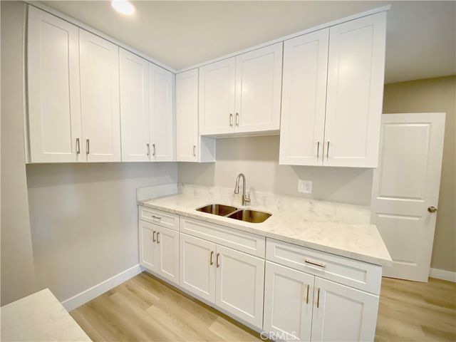 a kitchen with white cabinets and sink