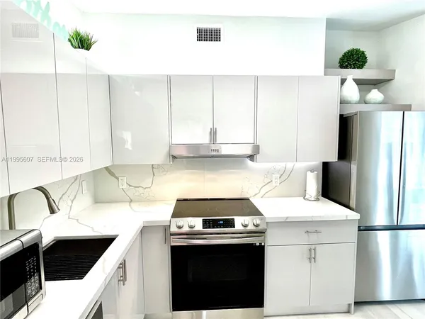 a kitchen with a sink a stove and white cabinets