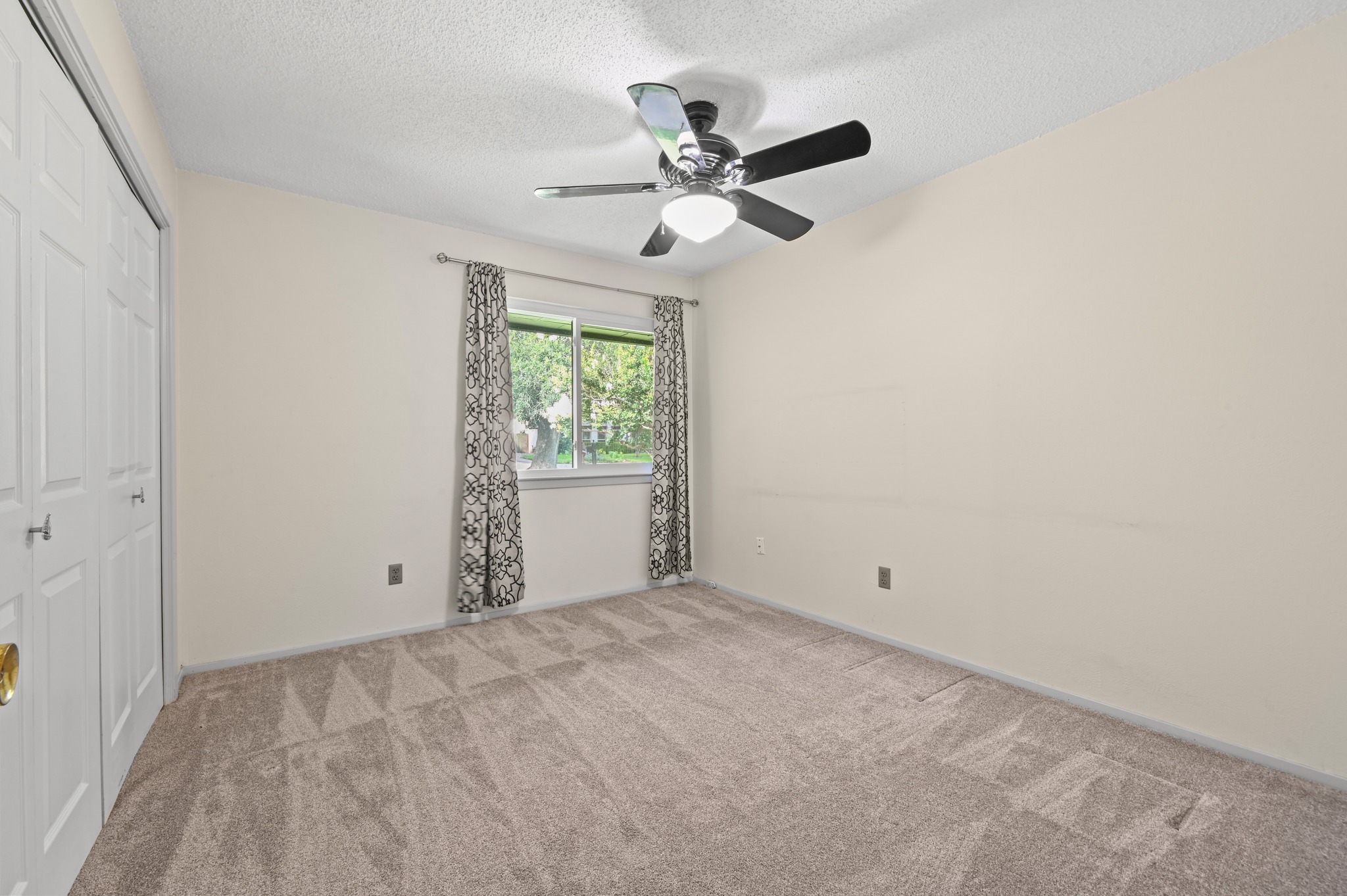 10504 Hard Rock Road Austin, TX 78750 - Photo 20 of 28 A comfortable bedroom features plush carpeting, a wide window with patterned curtains, and an overhead ceiling fan for optimal airflow.