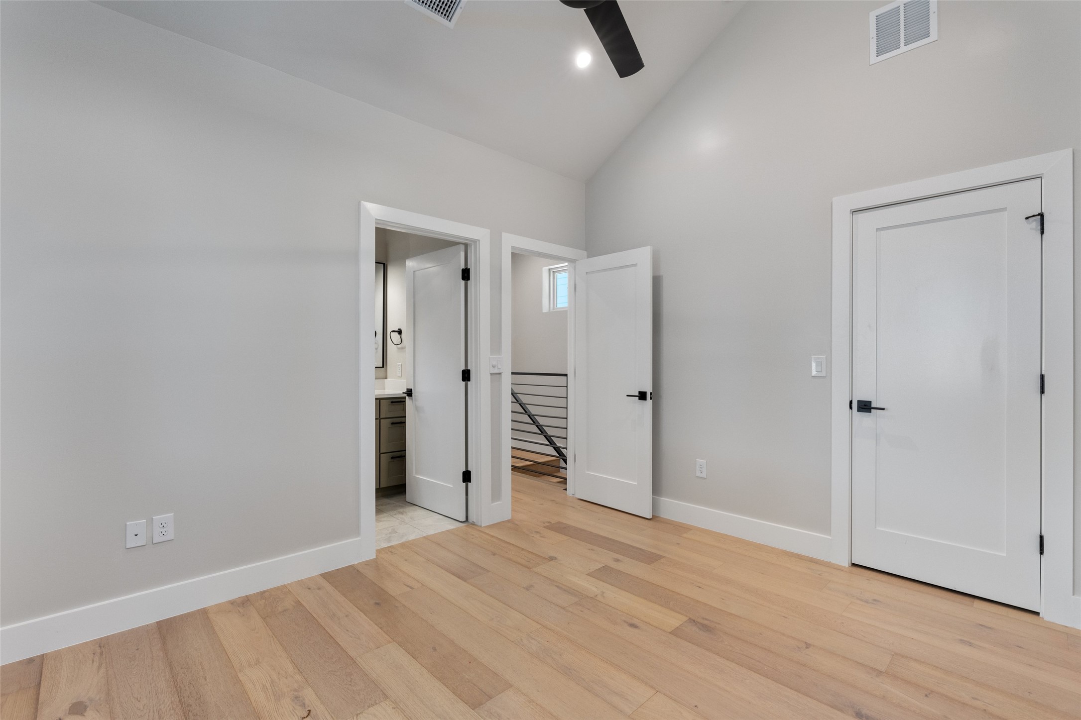 5200 Grover Avenue Austin, TX 78756 - Photo 17 of 32 Spacious primary bedroom featuring vaulted ceilings, light wood-finish flooring, white baseboards, and white interior doors with matte black hardware. A full private en-suite bathroom and walk-in closet.