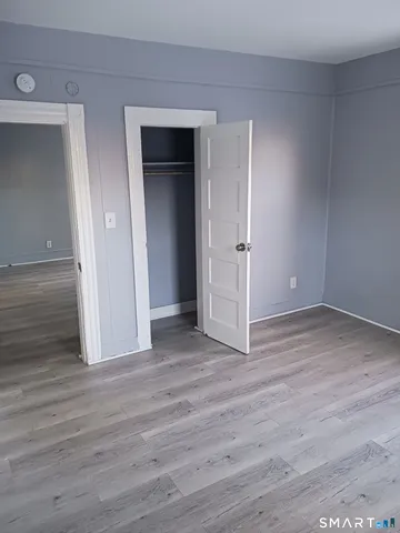 an empty room with wooden floor & closet area