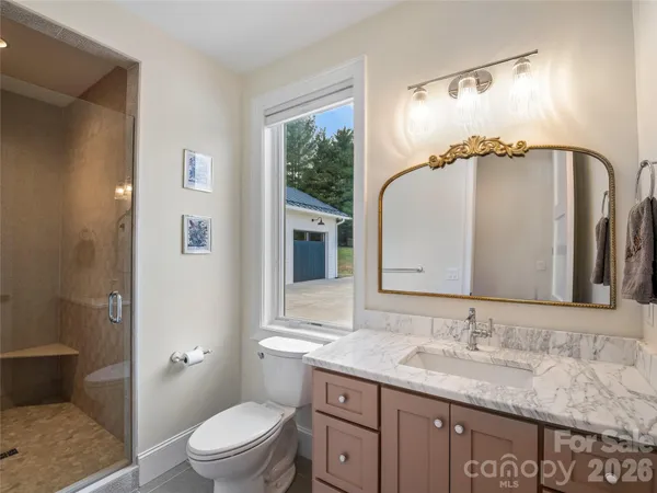 a bathroom with a granite countertop sink mirror vanity and toilet