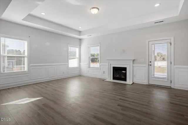 an empty room with wooden floor fireplace and windows