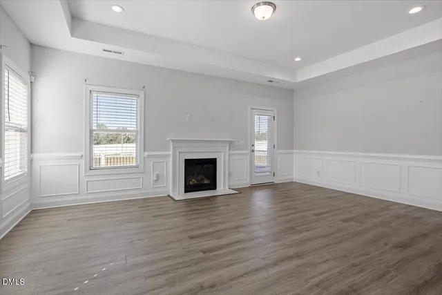 an empty room with wooden floor fireplace and windows