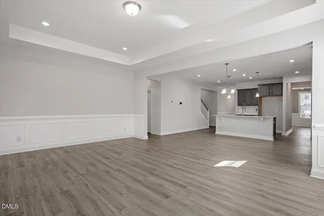 a view of an empty room with wooden floor and kitchen