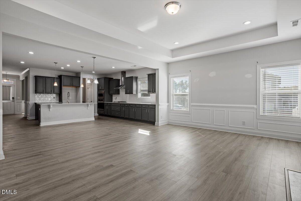 114 Stephens Timberline View Clayton, NC 27520 - Photo 18 of 43 an empty room with wooden floor and kitchen view
