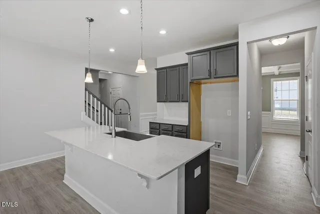 a kitchen with a sink a refrigerator and wooden floor