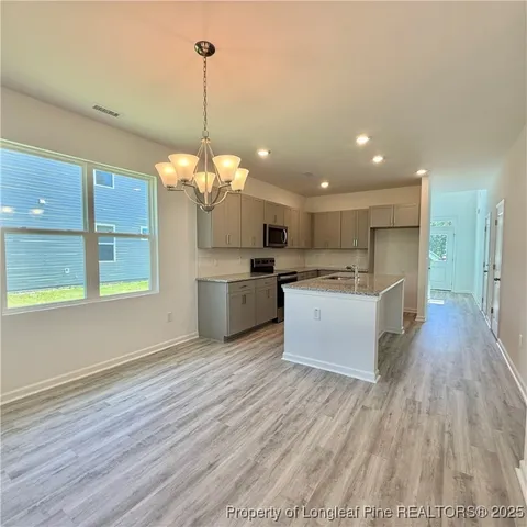 a view of a kitchen with kitchen island a sink wooden floor and a chandelier