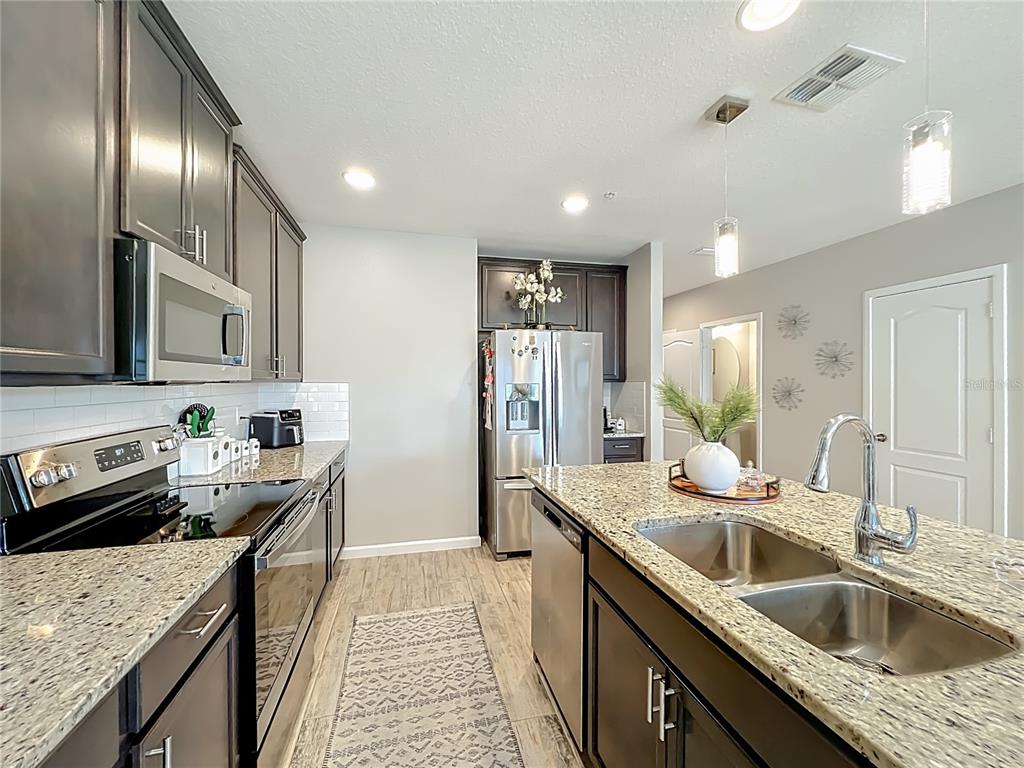 381 Smugglers Way Apopka, FL 32712 - Photo 8 of 53 a kitchen with stainless steel appliances granite countertop a sink stove and refrigerator