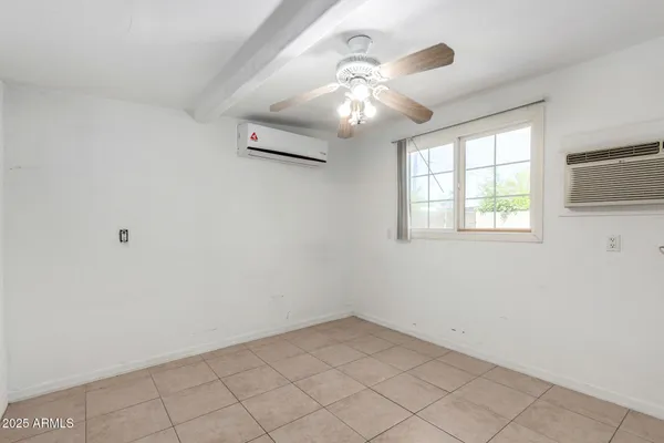 en empty room with windows and chandelier fan