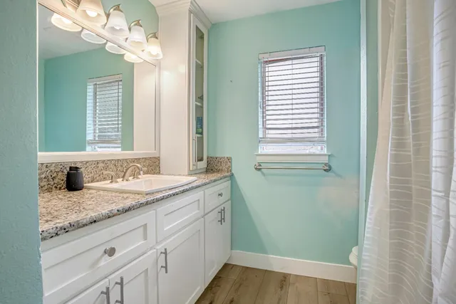 a bathroom with a granite countertop sink a toilet and mirror