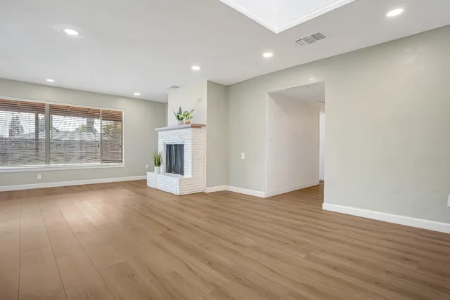 an empty room with wooden floor and a fireplace