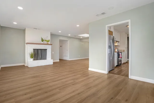 an empty room with wooden floor and a fireplace