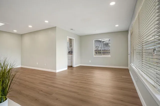 a view of an empty room with wooden floor and a window