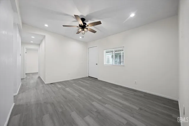 an empty room with wooden floor fan and windows