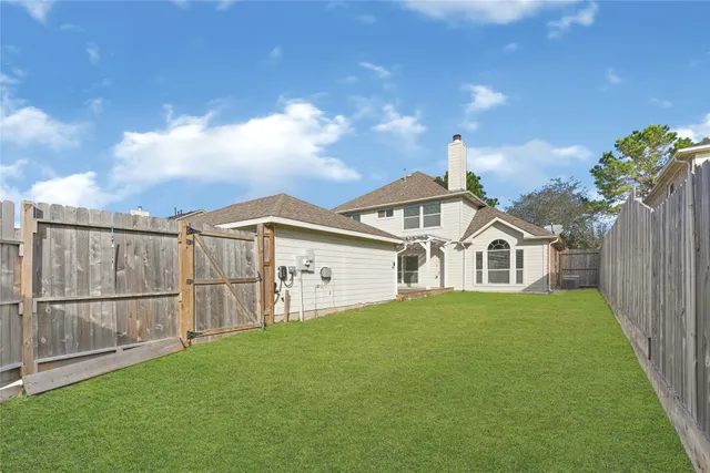 a view of a white house with a yard and wooden fence