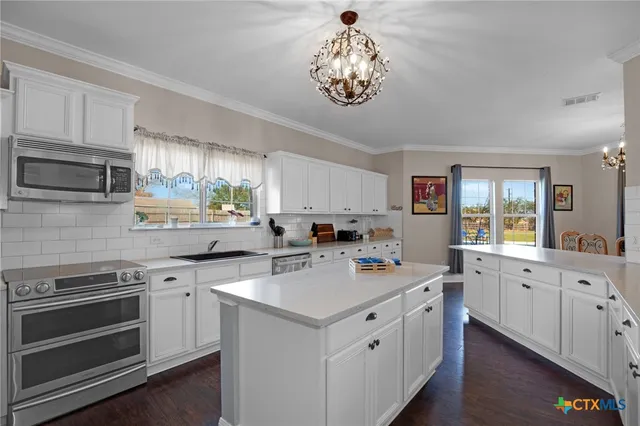 a large kitchen with kitchen island white cabinets and stainless steel appliances
