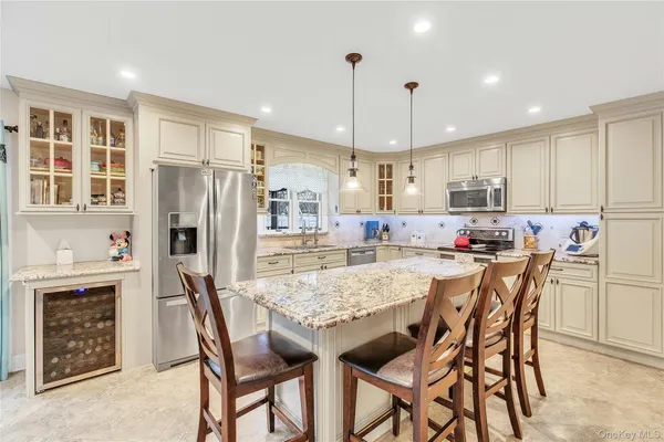a kitchen with stainless steel appliances granite countertop a dining table chairs refrigerator and cabinets