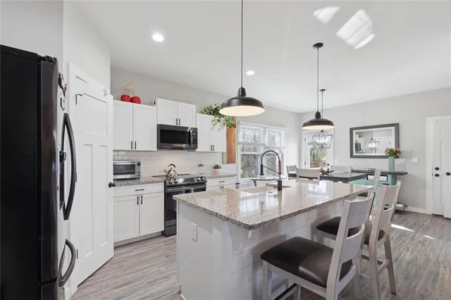 a kitchen with stainless steel appliances a stove a sink a refrigerator a center island a stove and a center island