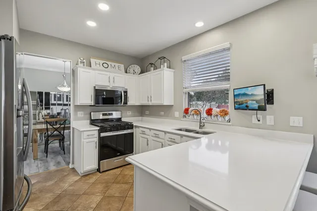 a large white kitchen with stainless steel appliances granite countertop a stove and a sink