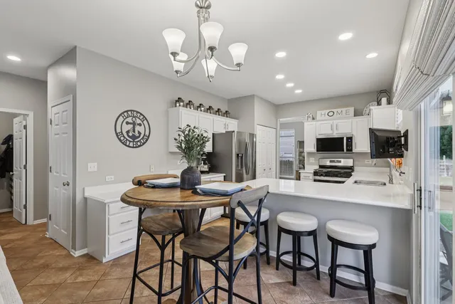 a view of a dining room with furniture a kitchen and chandelier