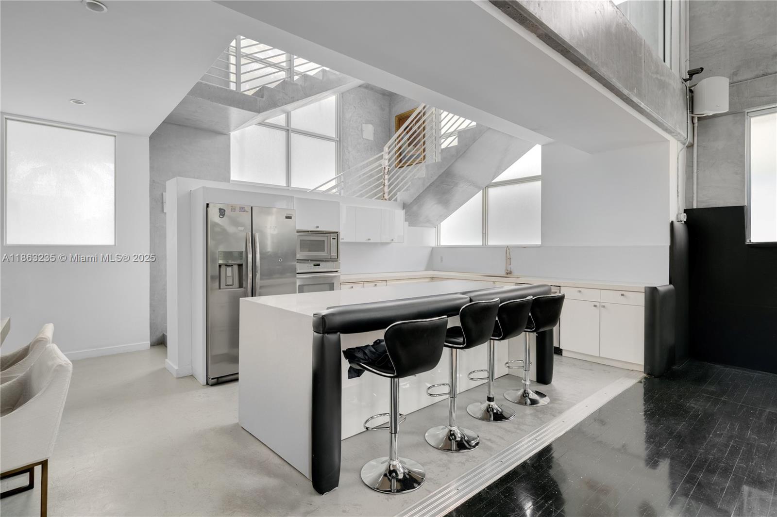 980 West 48th Street Miami Beach, FL 33140 - Photo 7 of 10 a kitchen with stainless steel appliances a table chairs and a refrigerator