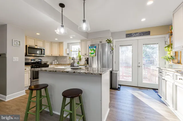 a kitchen with stainless steel appliances granite countertop a refrigerator a sink dishwasher a stove and white cabinets with wooden floor