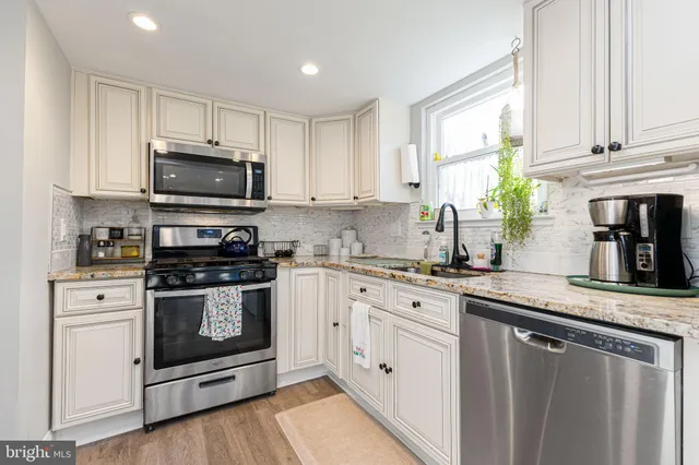 a kitchen with granite countertop white cabinets a sink and appliances