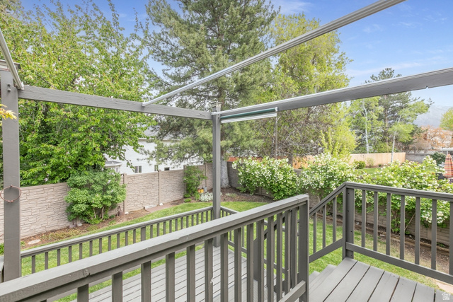 10183 Hickory Point Drive Sandy, UT 84092 - Photo 30 of 36 Expansive wooden deck with coordinating railings and stairs overlooking a landscaped backyard