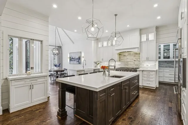 a large white kitchen with a large island oven a sink appliances and a couch