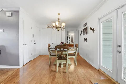 a dining room with wooden floor a chandelier a wooden table and chairs