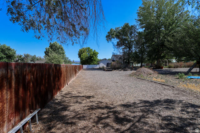 270 East 100 North Monroe, UT 84754 - Photo 64 of 65 Expansive outdoor space featuring a tall privacy fence, mature trees, and a gravel surface