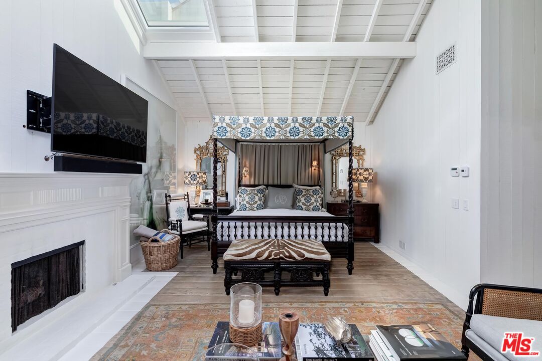 23618 Malibu Colony Road, Unit 56 Malibu, CA 90265 - Photo 16 of 29 a bedroom with furniture a fireplace and a flat tv screen