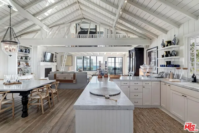 a large white kitchen with kitchen island a stove a table and chairs in it