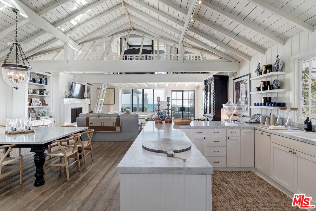 23618 Malibu Colony Road, Unit 56 Malibu, CA 90265 - Photo 4 of 29 a large white kitchen with kitchen island a stove a table and chairs in it