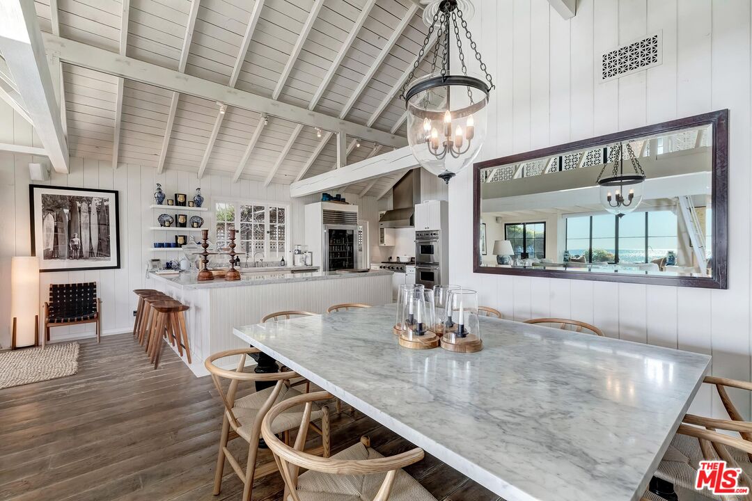23618 Malibu Colony Road, Unit 56 Malibu, CA 90265 - Photo 6 of 29 a dining room with wooden floor a chandelier a wooden table and chairs