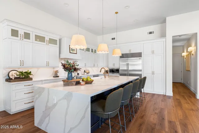 a kitchen with stainless steel appliances kitchen island granite countertop a table chairs and a refrigerator
