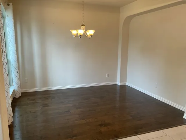 an empty room with wooden floor door and windows
