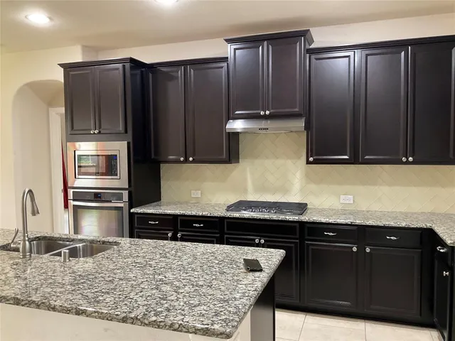 a kitchen with granite countertop a sink a counter top space and windows