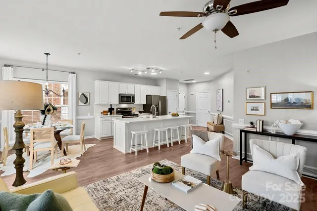 a living room with furniture kitchen view and a chandelier