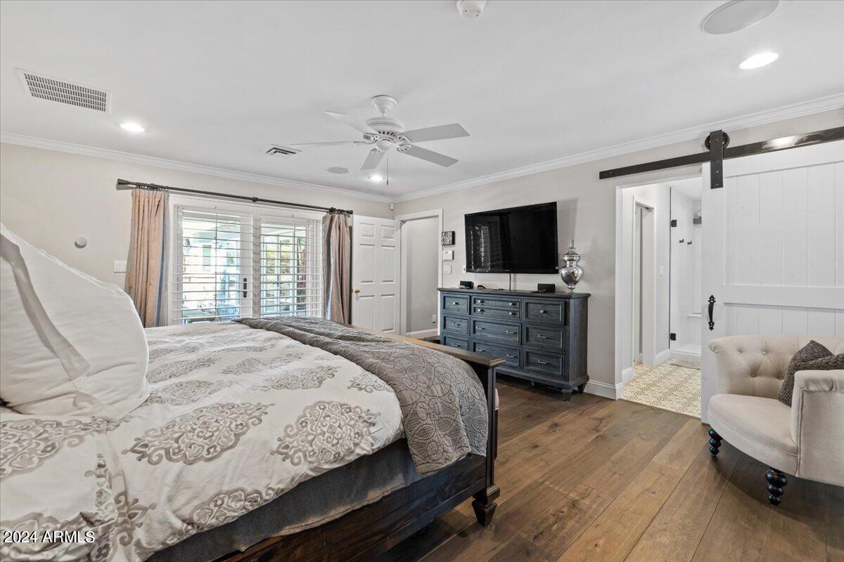 3841 East Elm Street Phoenix, AZ 85018 - Photo 29 of 72 a spacious bedroom with a bed a tv and wooden floor